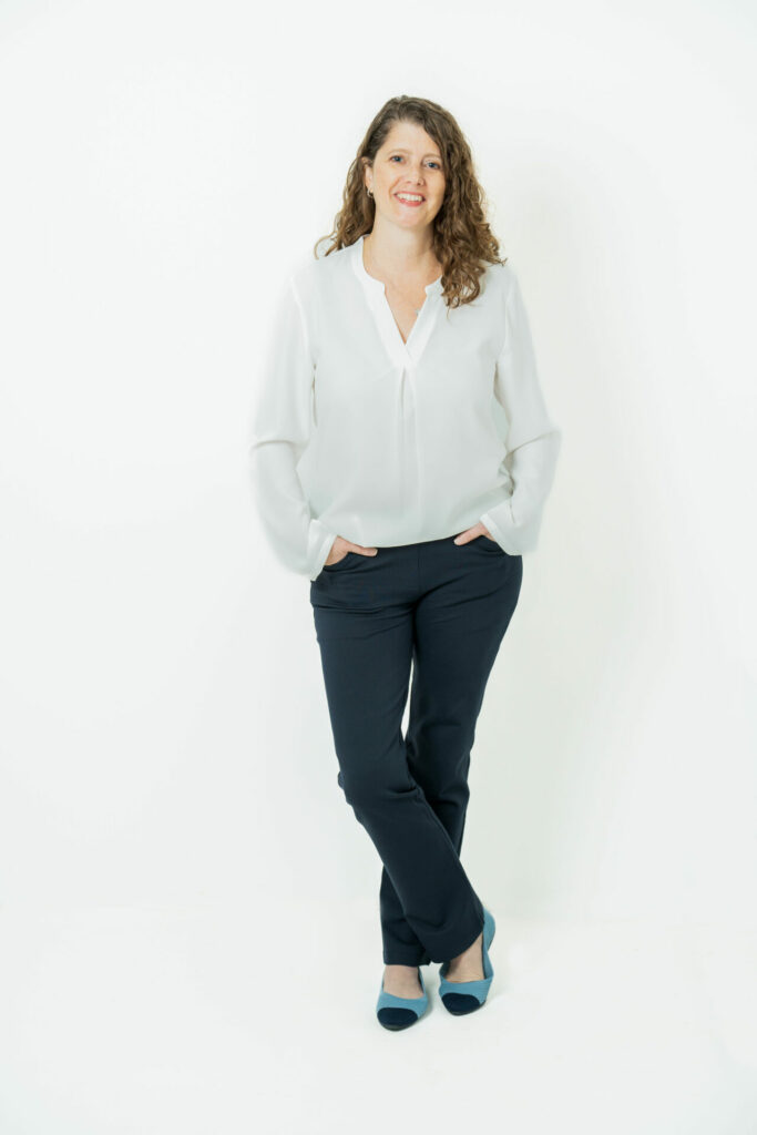Allison Johs Legal Ease Consulting, standing and wearing a white top and blue pants